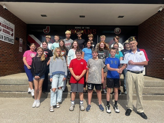 students stand in front of the school with american legion officer