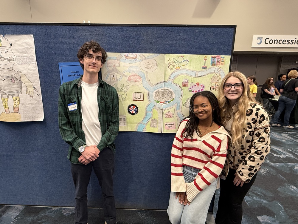 Students pose in front of their poster.