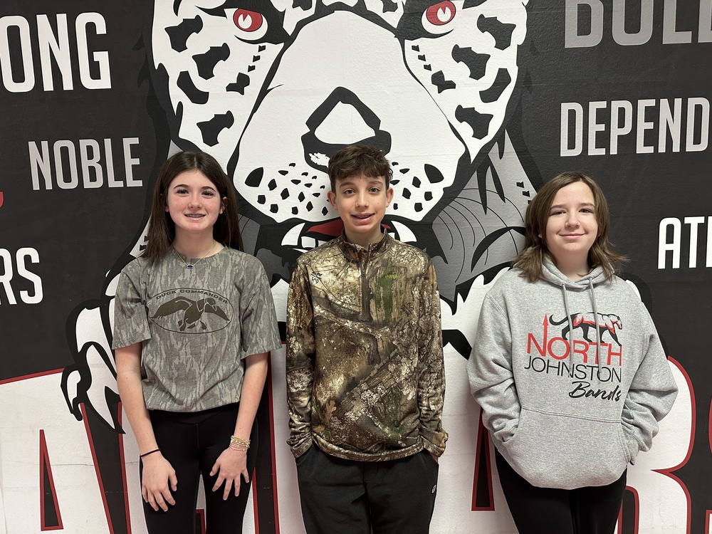 3 8th grade students in front of the jaguar mural 