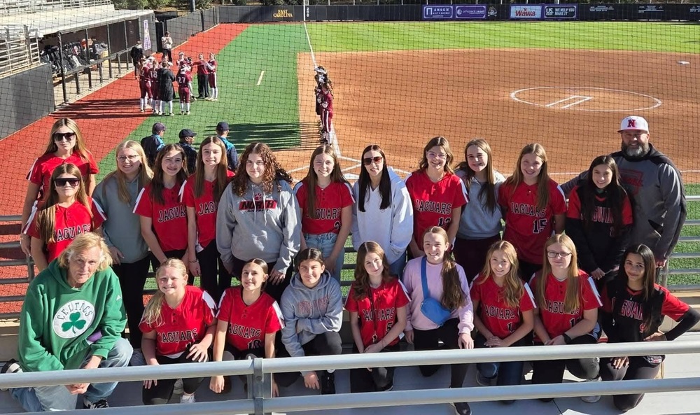 Picture of the njms softball team and coaches at ecu softball stadium 