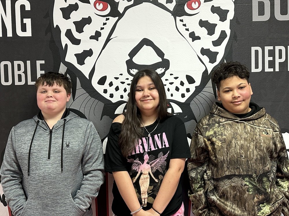 3 students standing in front of the jaguar mural