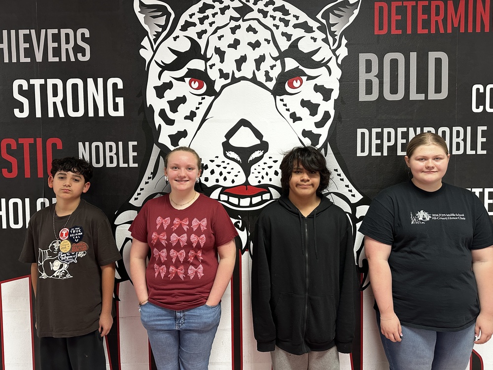 4 7th graders standing in front of the jaguar mural 