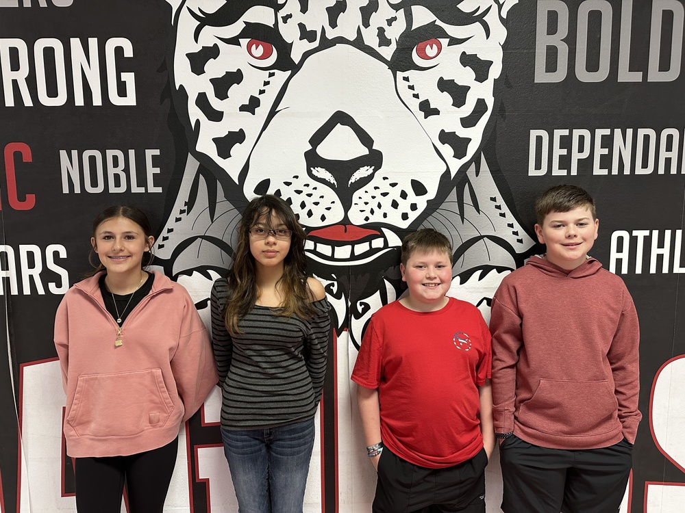 picture of 4 6th grade students standing in front of the jaguar mural 