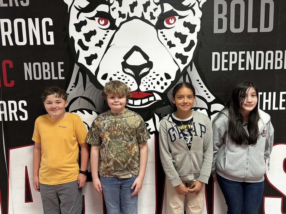 4 6th grade students standing in front of the jaguar mural 