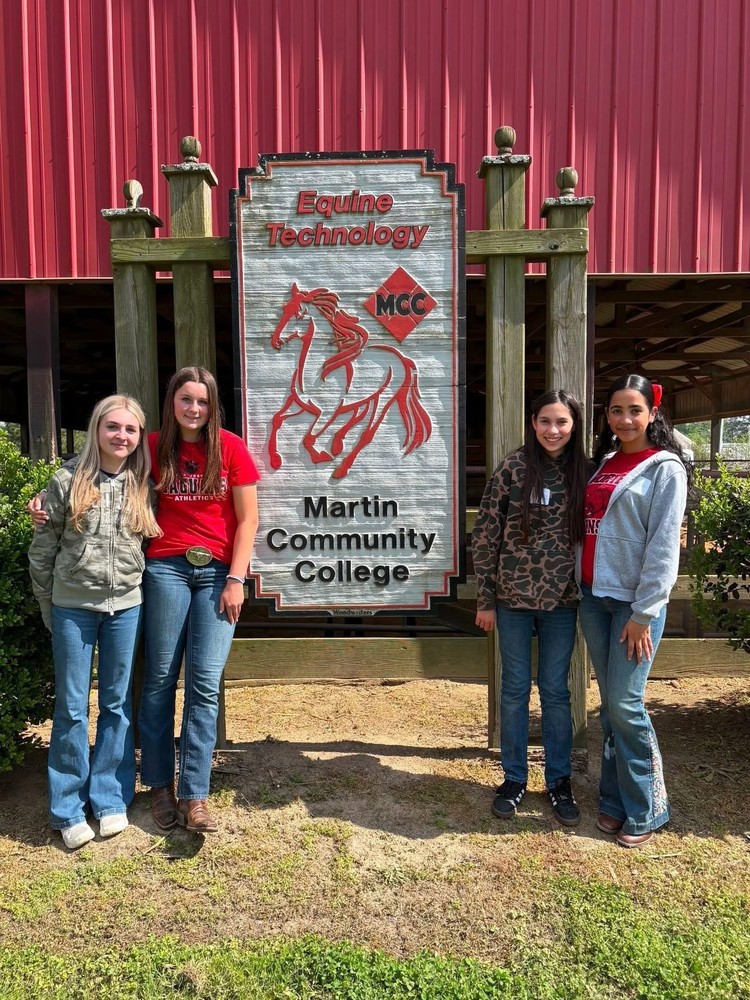 4 female ffa members outside a red barn and infront of a sign that say equine technology martin community college