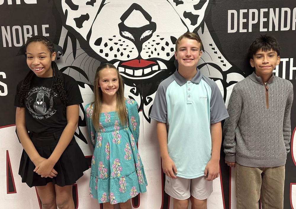 picture of 4 6th grade students standing in front of the jaguar mural