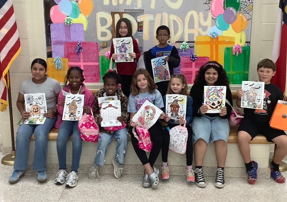 students seated in two rows holding their winning coloring page