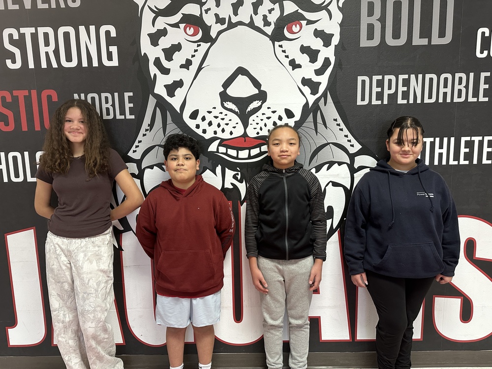 Picture of 4 7th grade students standing in front of the jaguar mural