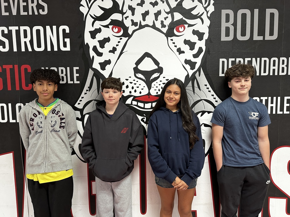 4 8th grade students standing in front of the jaguar mural 