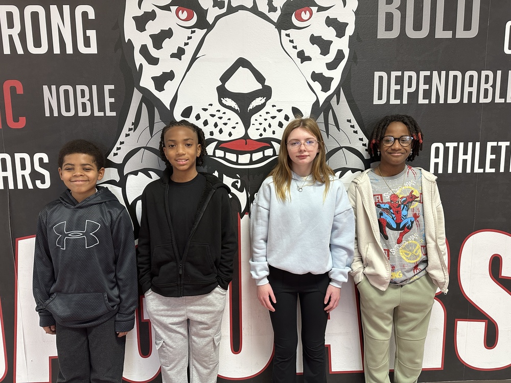 picture of 4 6th grade students standing in front of the jaguar mural