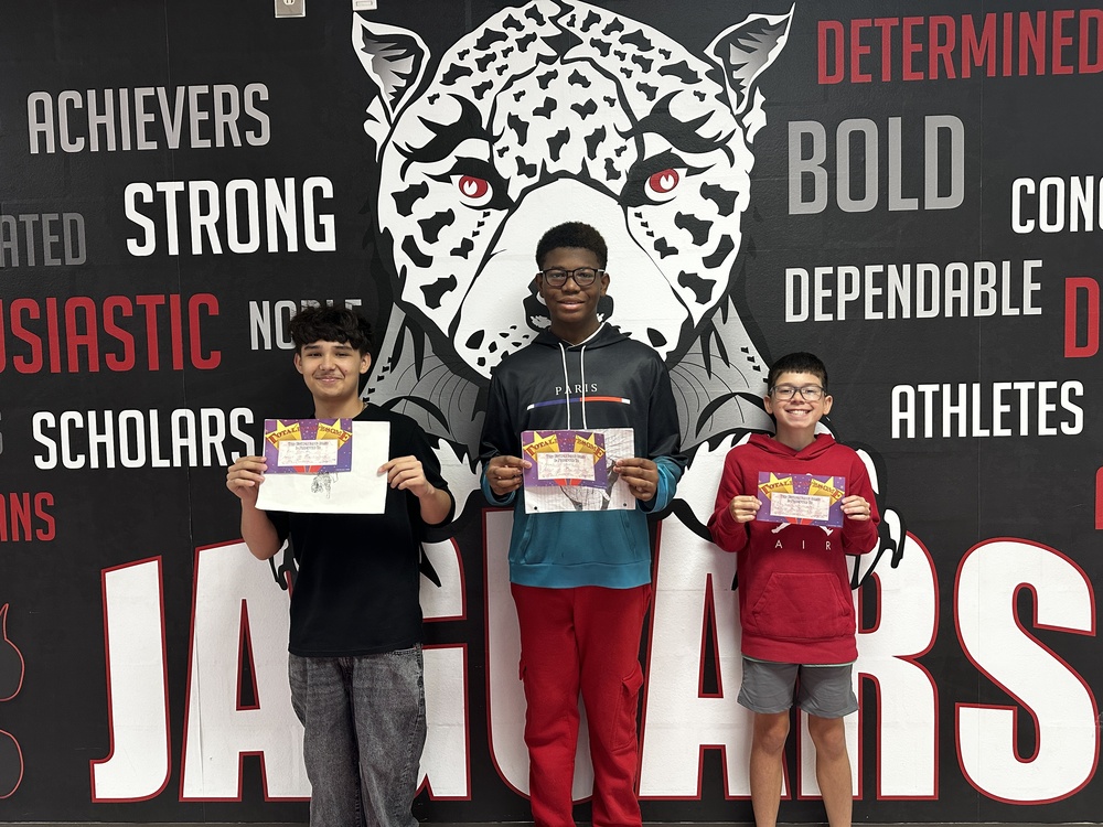Picture of 3 male students standing in front of the jaguar mural holding certificates