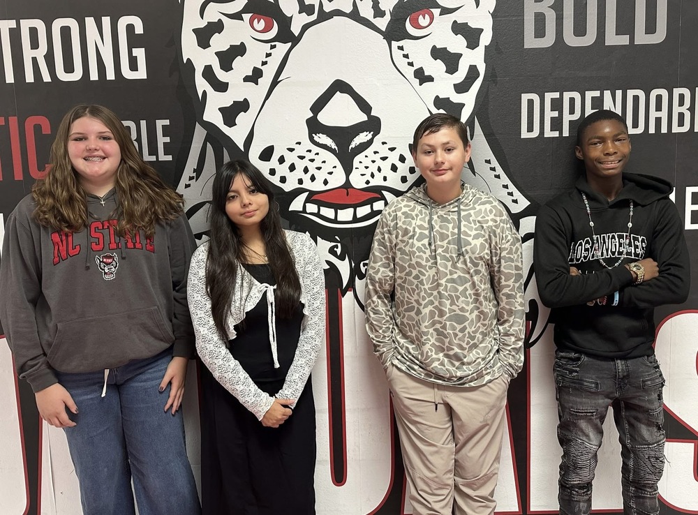 4 8th grade students standing in front of the jaguar mural