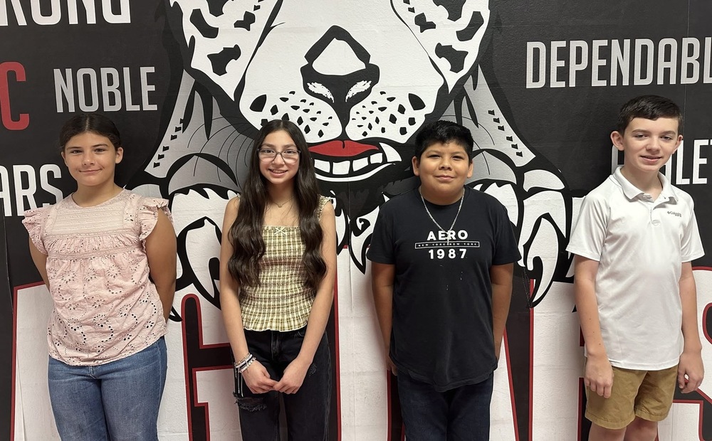4 7th grade student standing in front of the jaguar mural