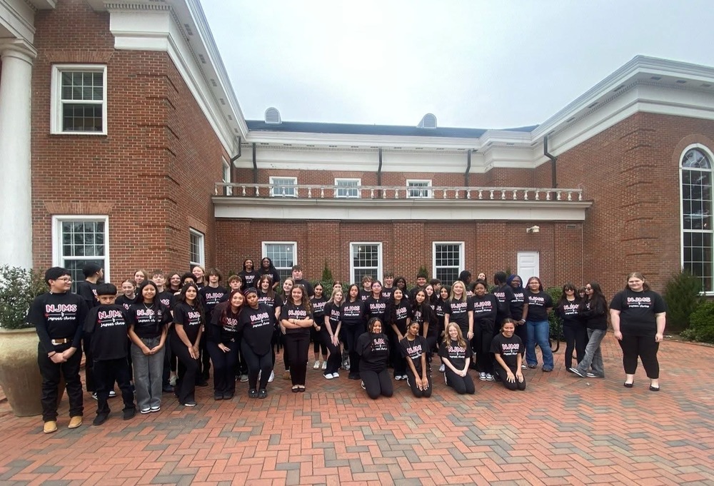 Group of njms chorus students all wearing black shirts standing outside of campbell university 