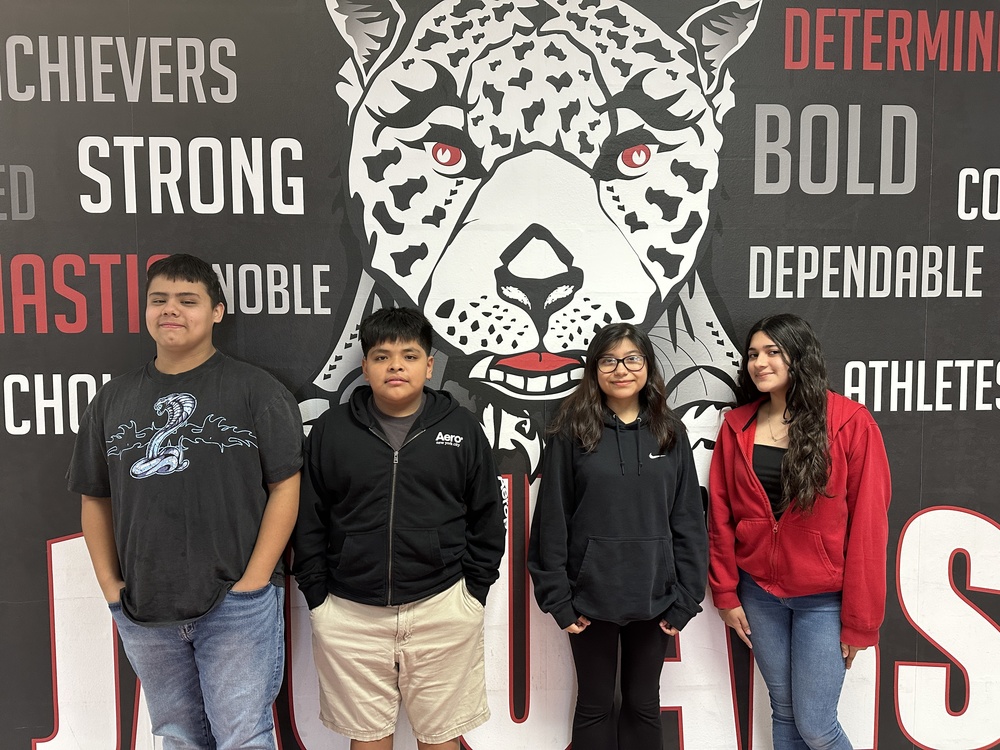 Picture of 4 8th grade students standing in front of the jaguar mural
