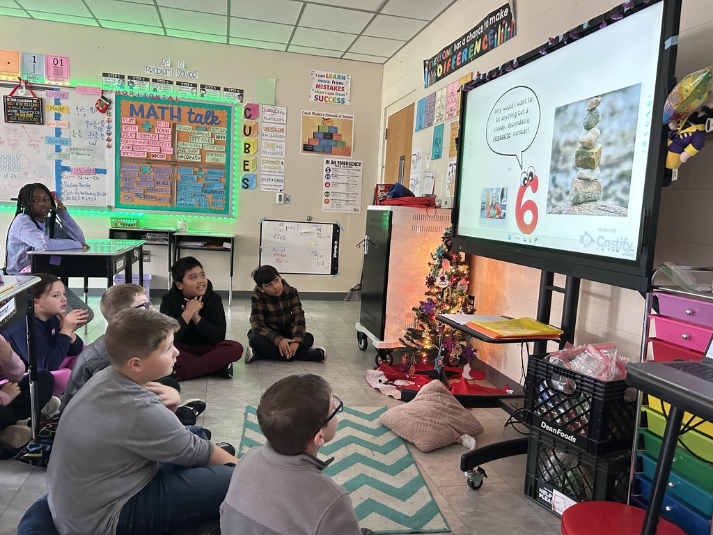 Group of 4th grade students viewing a book on the smartboard called The Battle of 6 versus 7