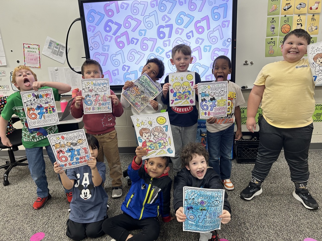 Group of first graders boys in front of smart board holding coloring page 
