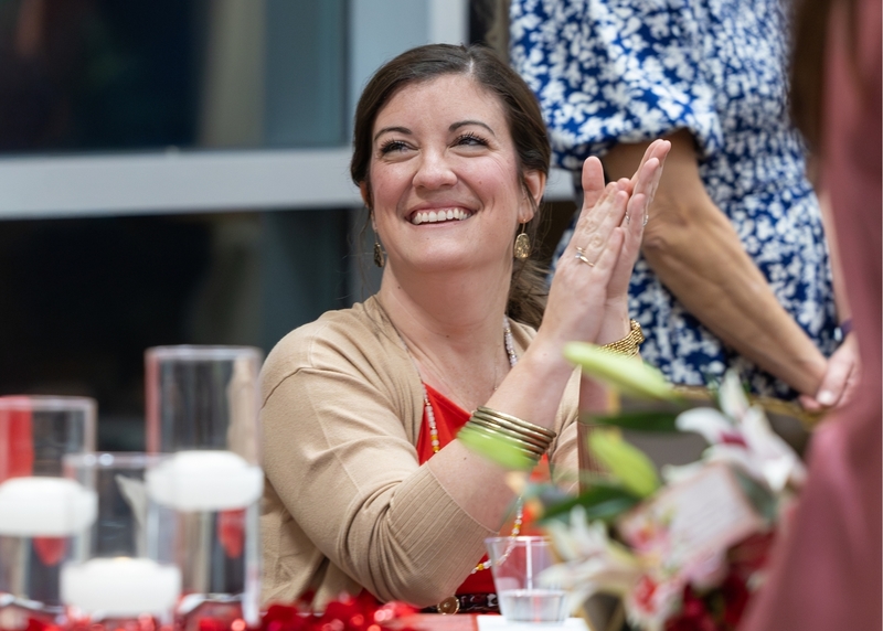 An attendee smiles and claps as a Leading with the Heart honoree is called to the stage to be recognized.