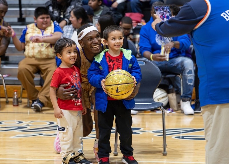 A Harlem Wizards player takes a picture with two small children at the event.
