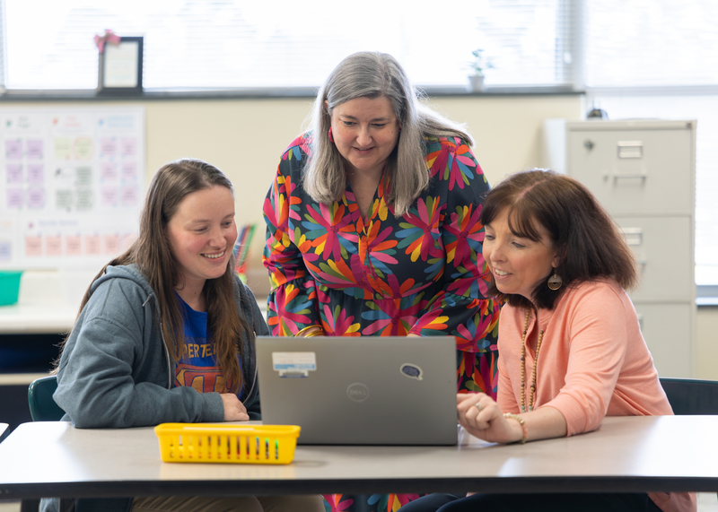 Lauren Strickland works with two teachers on the computer.