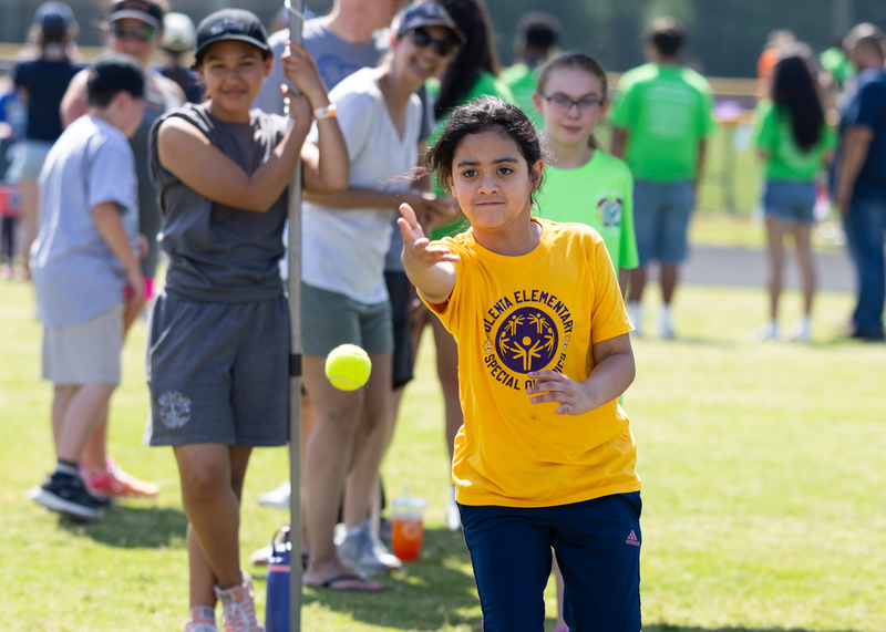 A Polenta Elementary student takes her turn during the Tennis Ball Throw as volunteers look on in excitement.