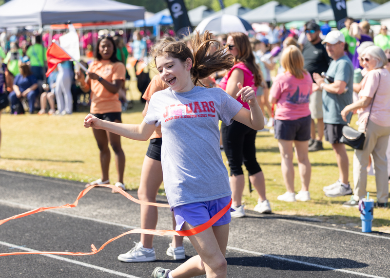 A girl smiles as she crosses the finish line at Special Olympics Johnston County Spring Games.