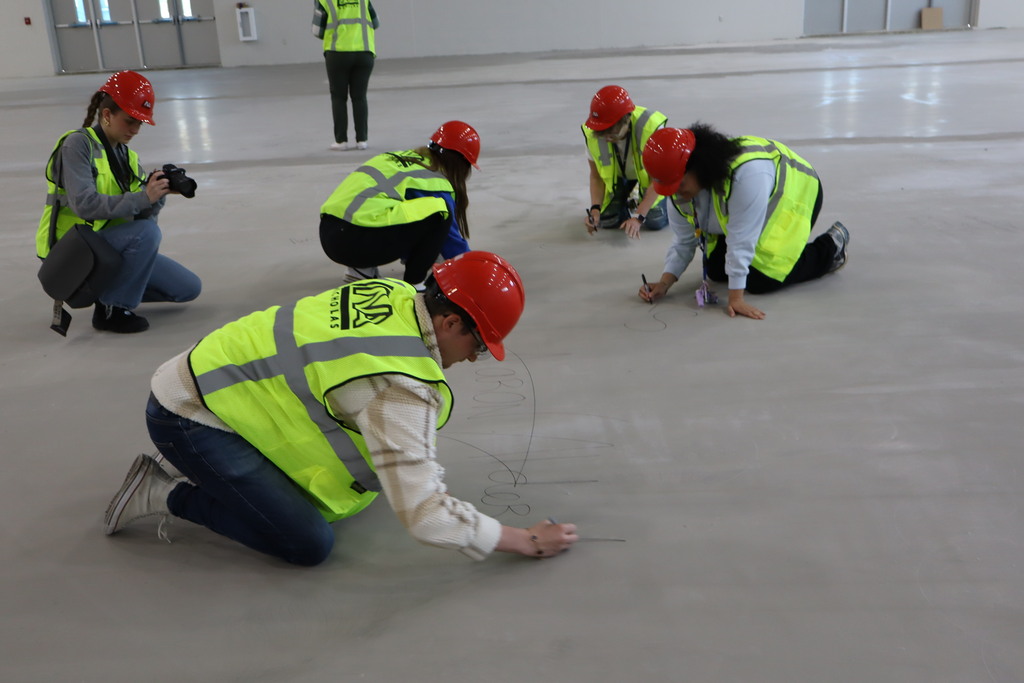 Hufford staff sign their names on the subfloor of the new gymnasium