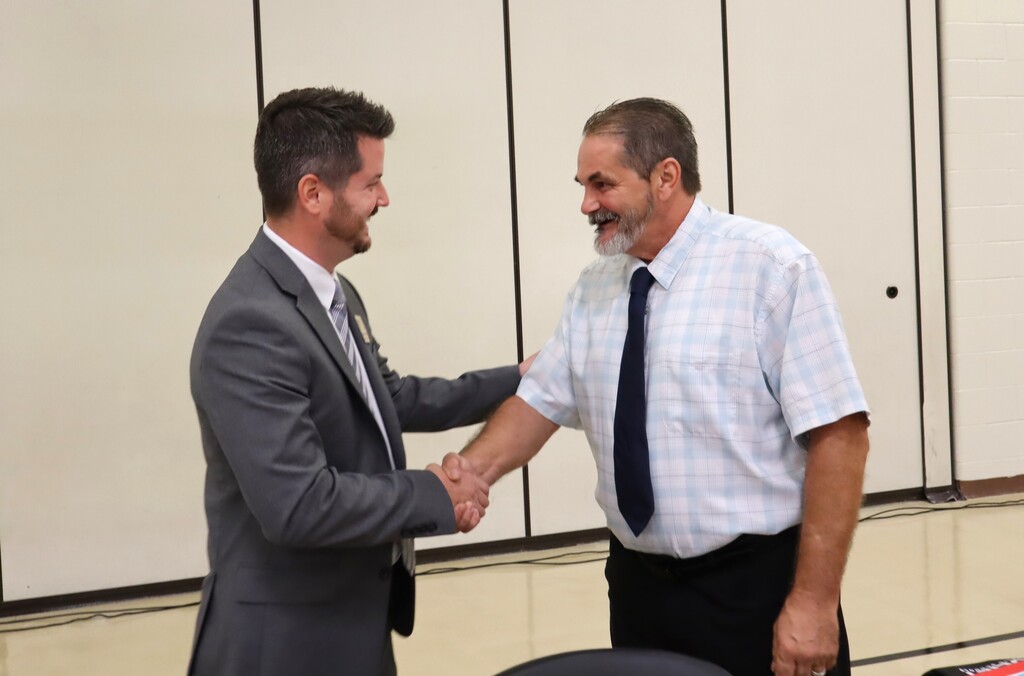 School board members Matthew Pritz and Andrew Smith shake hands