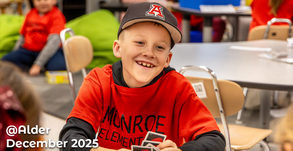 Student smiling while wearing alder hat and monroe shirt