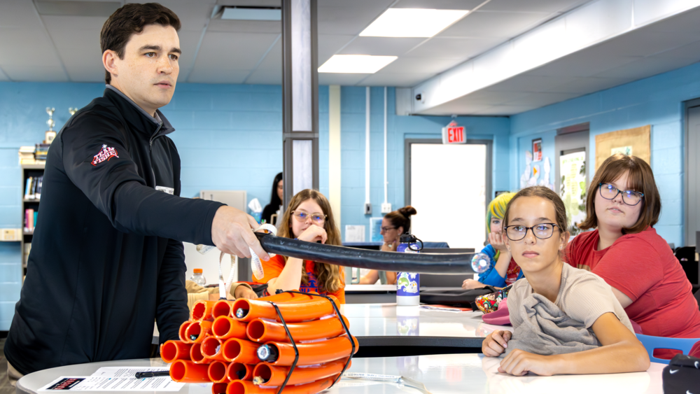 Team Fischel employees discuss fiber cables with jr high students