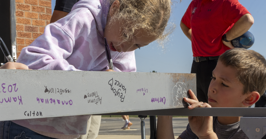 students at beam signing