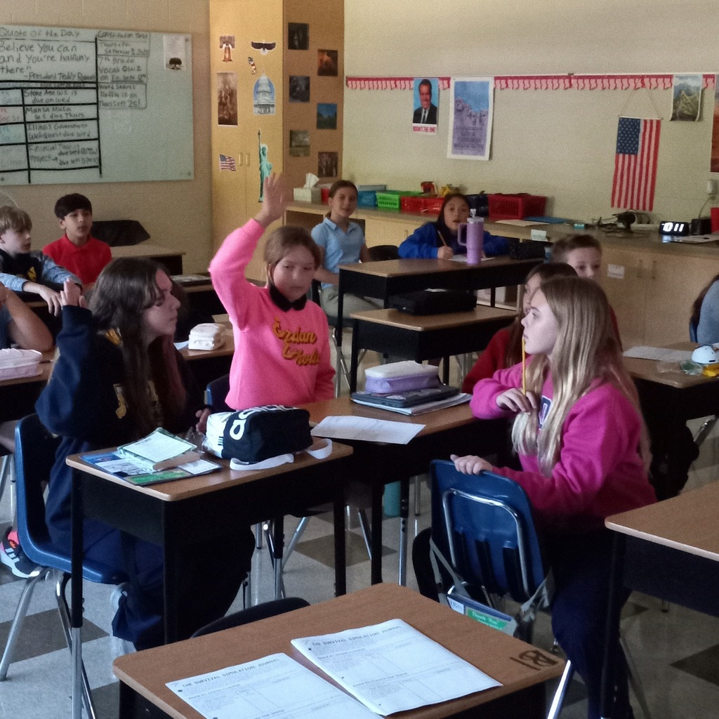 students working together in groups. One student has their hand raised