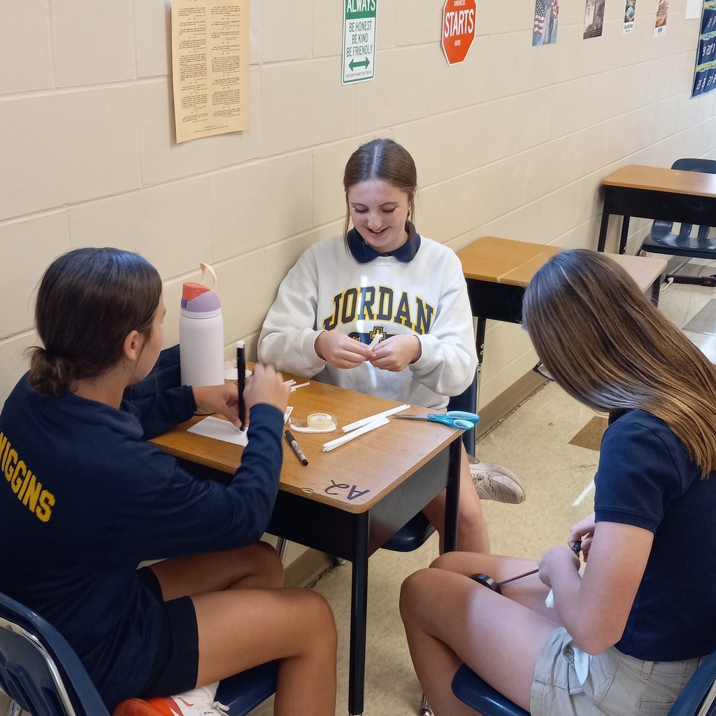 students using plastic straws and tape to build a ceremonial tower