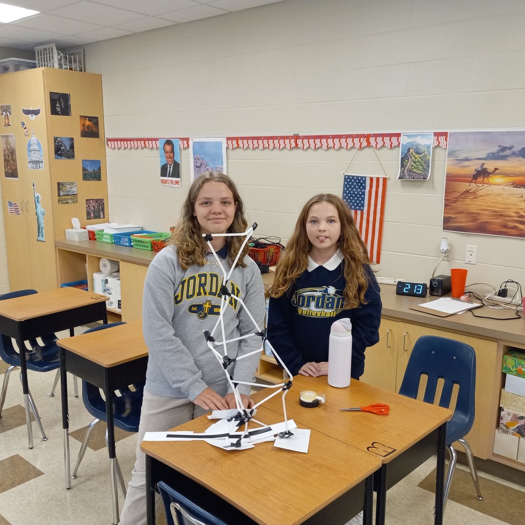 students posing in a classroom with their ceremonial tower made from straws and tape