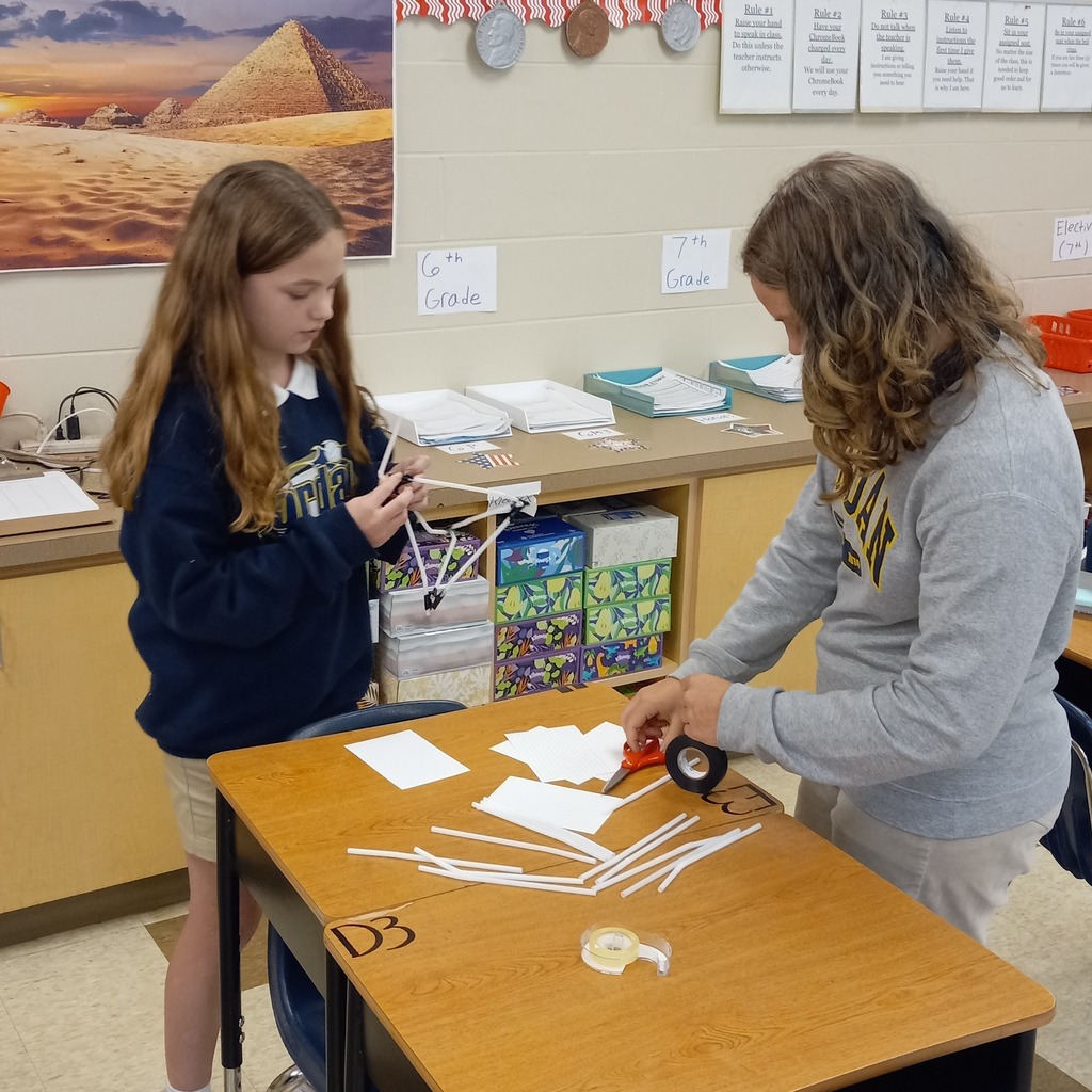 students using plastic straws and tape to build a ceremonial tower