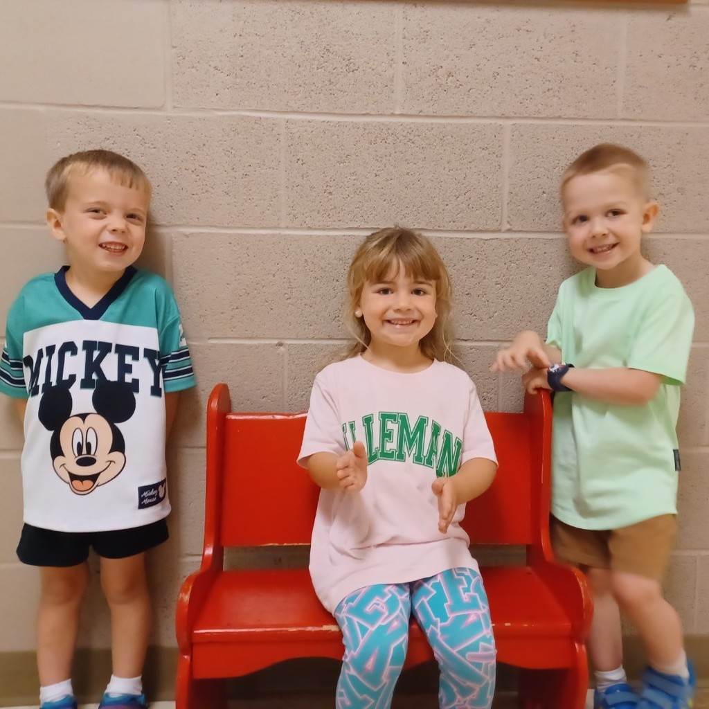 3 students posing near red bench