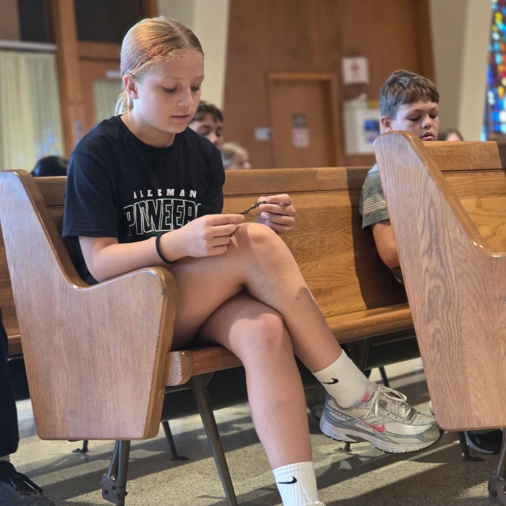 students sitting on pews praying the rosary