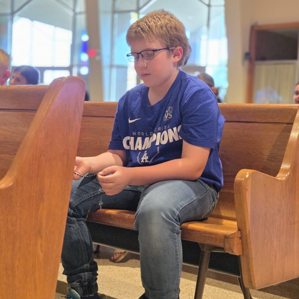 students sitting on pews praying the rosary