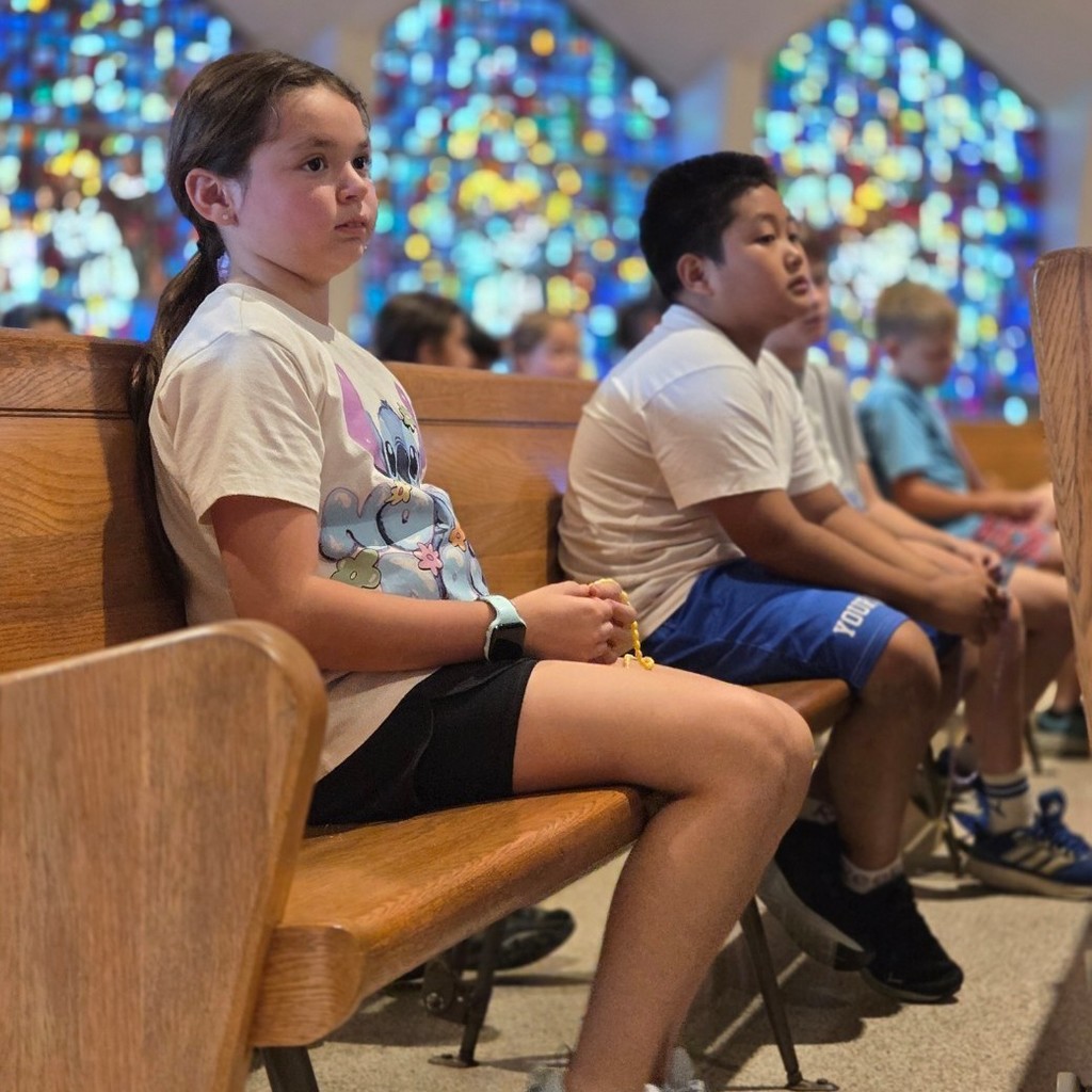 students sitting on pews praying the rosary