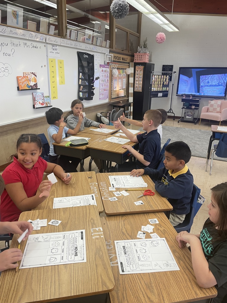 students writing a story together while seated at desks in a classroom
