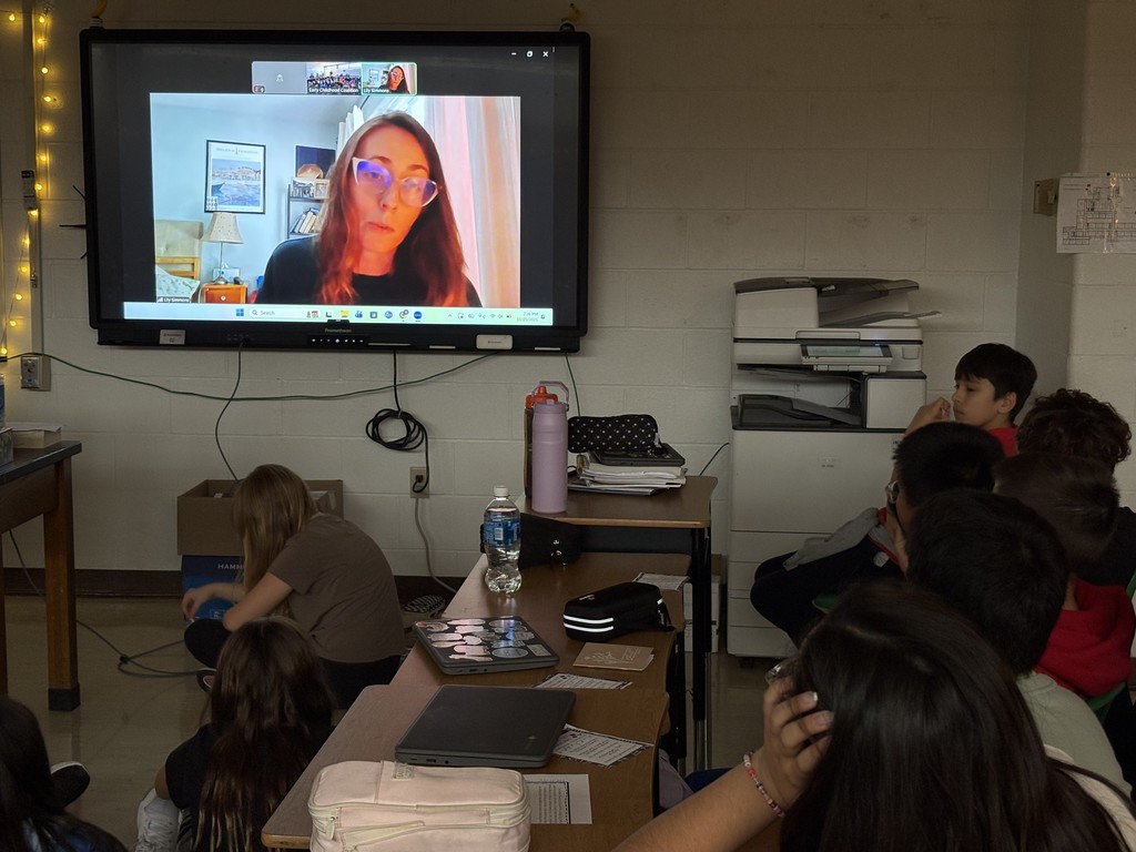 students seated at desks meeting with an author in a video call
