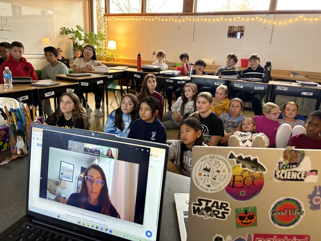 students seated at desks meeting with an author in a video call
