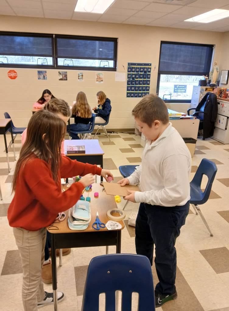 students using cardboard and tape to build a car