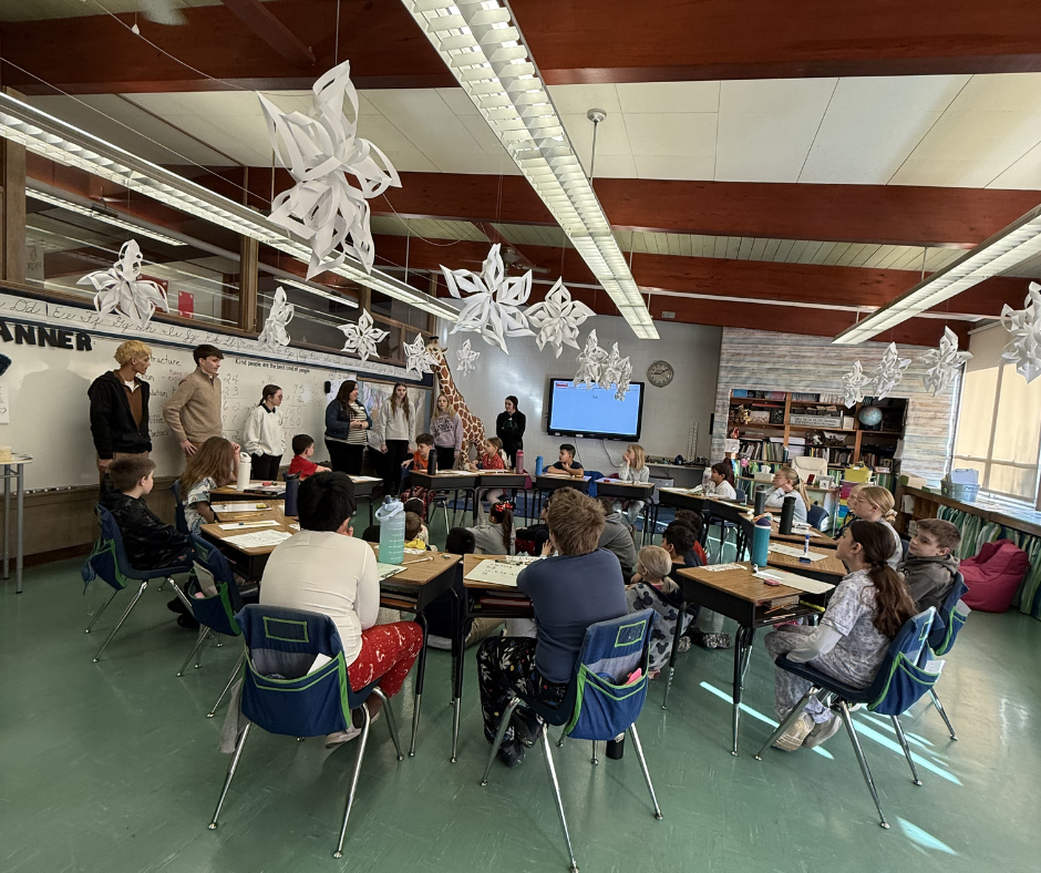 students seated at desks in a classroom listening to a presentation