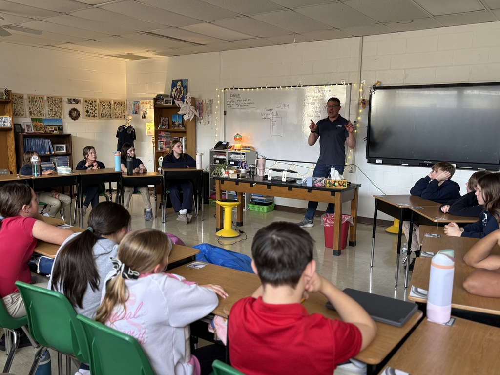 students seated at desks listening to guest speaker