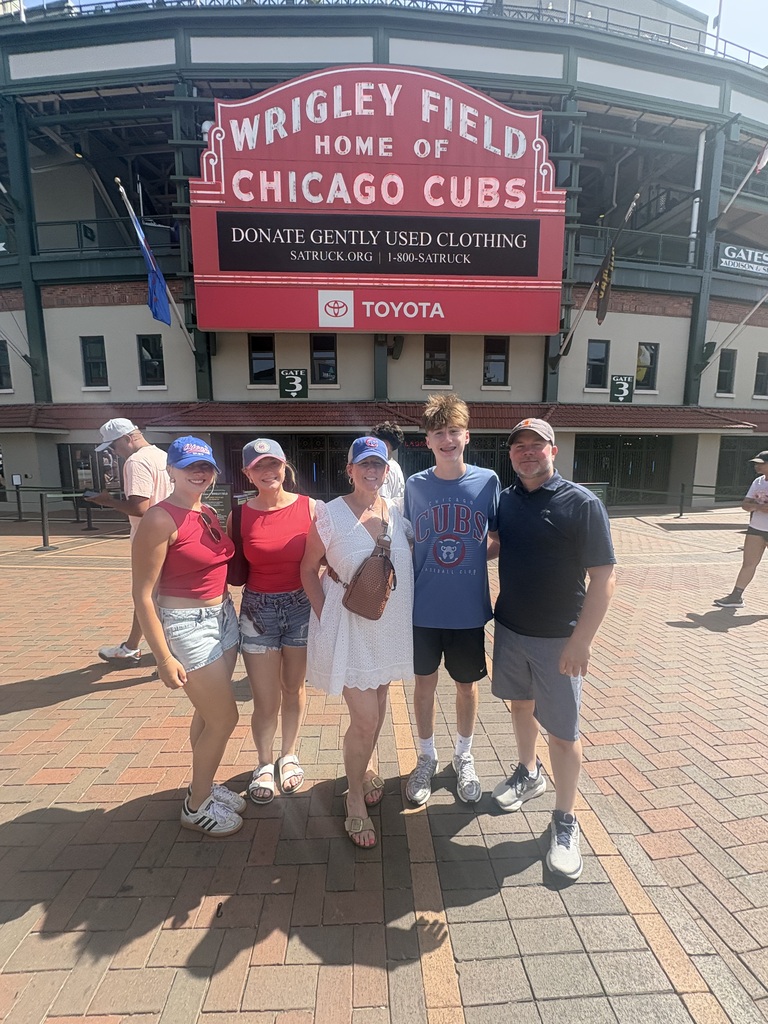 three women and two men pose in front of Wrigley Field main entrance