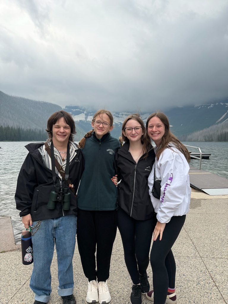 four people posing in front of a mountain in the distance