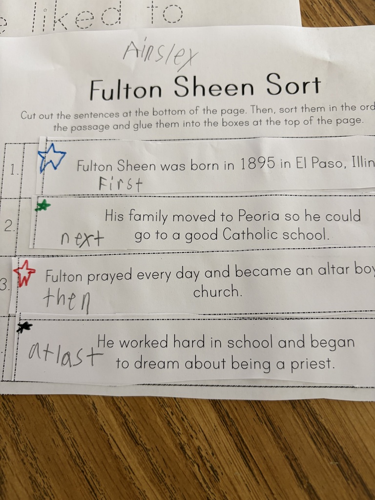 A close-up view of a student's completed sequencing worksheet titled "Fulton Sheen Sort". Strips of paper detailing chronological events in Fulton Sheen's life are glued in numbered order, with hand-written labels "First," "next," "then," and "at last" next to colorful drawn stars.