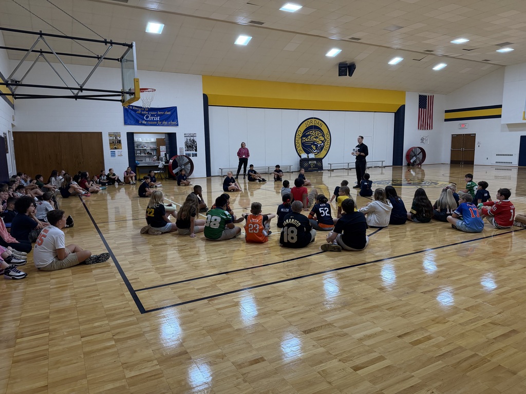 students sitting in the gym listening to a speaker