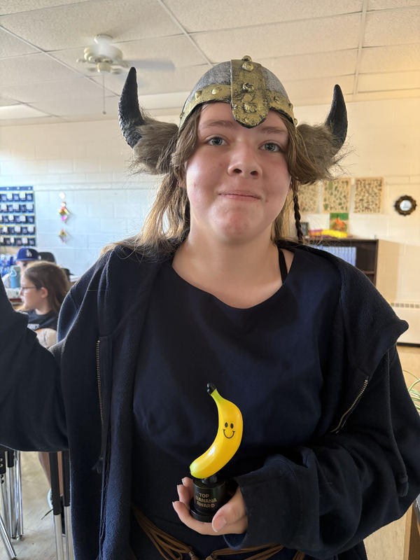 student posing with banana trophy